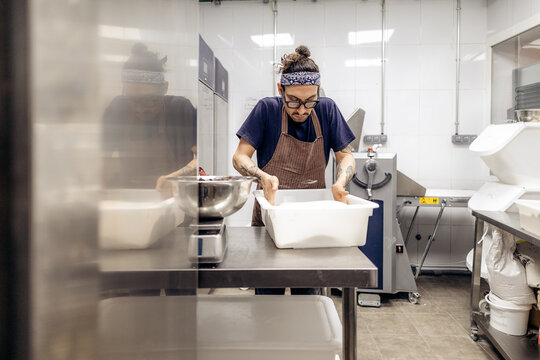Baker measuring flour in bakery kitchen