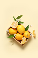 Wooden box of lemons with blooming branch on beige background