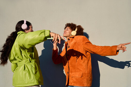 Two women dancing together with headphones outdoors