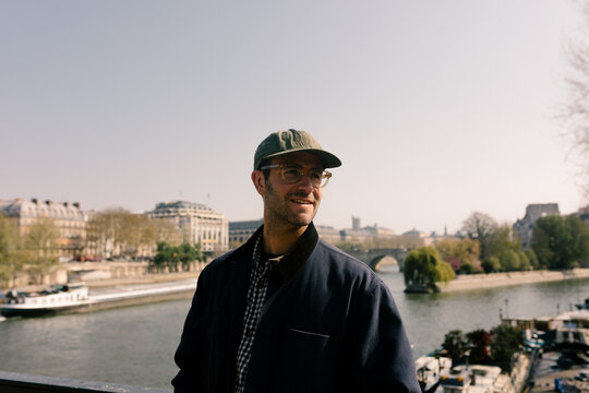 Young man smiling on a bridge over the Seine River in Paris