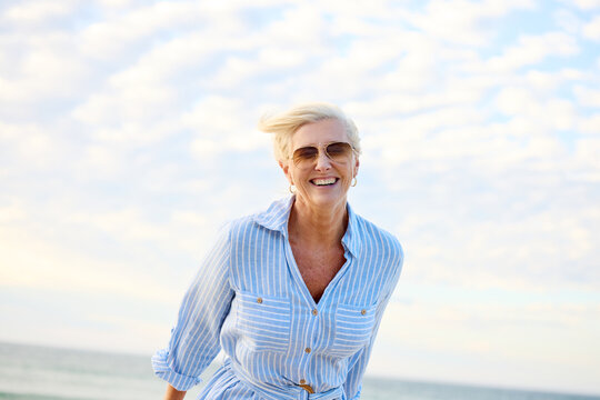 Woman Smiles at the Beach Under a Blue Sky