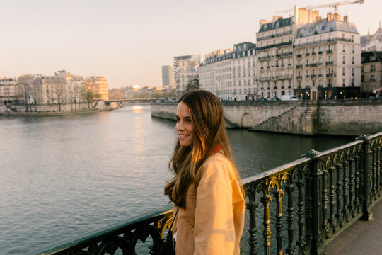 Female traveler poses along the Seine River at sunset in Paris