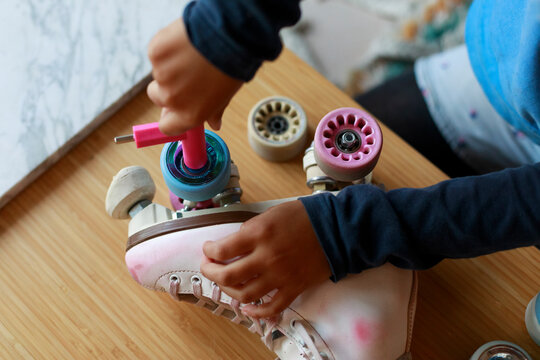 Child Repairs Roller Skates at Home on a Wooden Table
