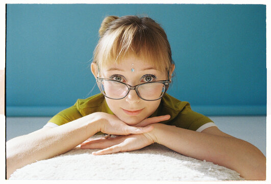 Young woman with glasses looks directly at the camera