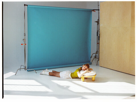 Model poses on the floor next to a round table in a studio