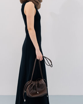 Faceless Minimal fashion look with black dress and brown leather bag