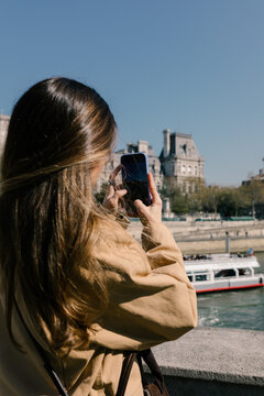 Tourist using a smartphone to photograph the Seine River