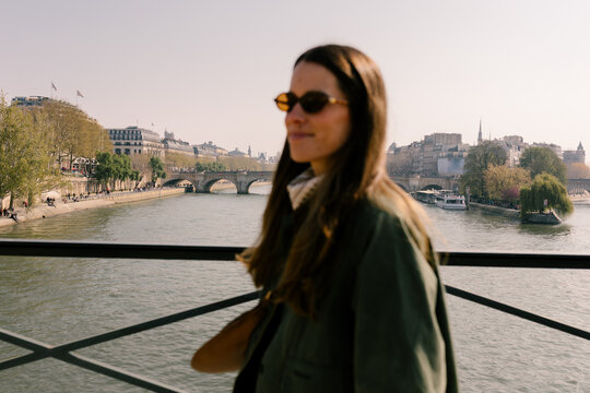 Woman smiling while posing on a bridge over the Seine River