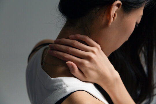 Person experiencing neck pain, massaging aching shoulder