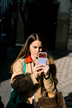 Tourist using her smartphone to take pictures of the streets of Paris