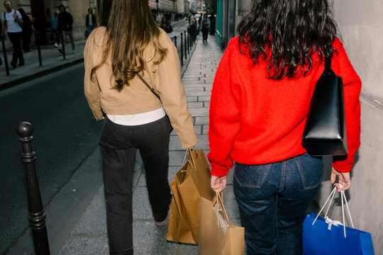 Women seen from behind walking with shopping bags in Paris