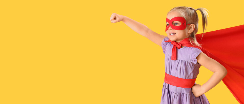 Cute little girl dressed as superhero on orange background