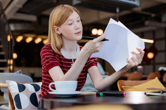 Woman reviews documents with coffee at a cafe.