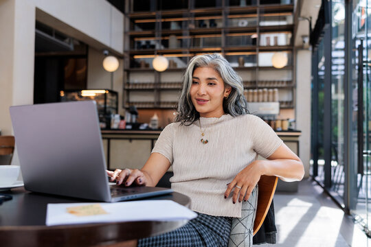 Woman working on laptop in cafe.