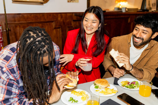 Group of Friends hanging out at restaurant eating hamburgers 