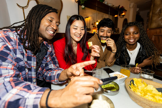 Group of Friends hanging out at restaurant checking smartphone