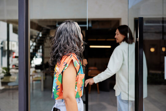 People entering a shop through glass doors.