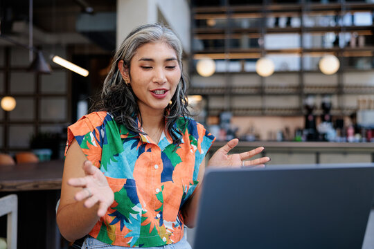 Woman with laptop gesturing during a video call.