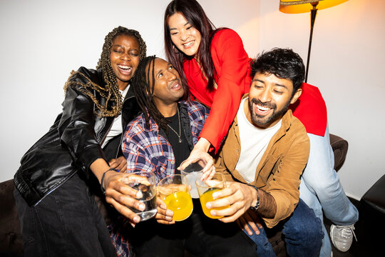 Friends hanging out at home party laughing and drinking 