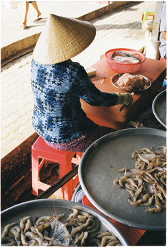 Woman sorts shrimp at a market in Vietnam during the day