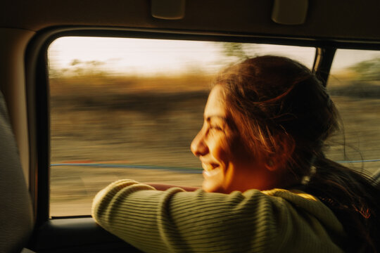 Smiling Woman Enjoys Ride With Window Down During Sunset