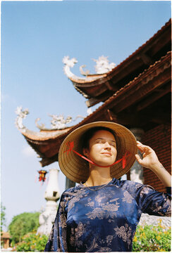 Woman wearing traditional hat enjoys sunlight in Vietnam