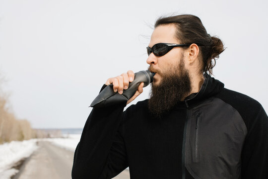 Portrait of stylish man drinking water from bottle outdoors 