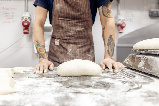 Baker standing ready with dough in bakery kitchen