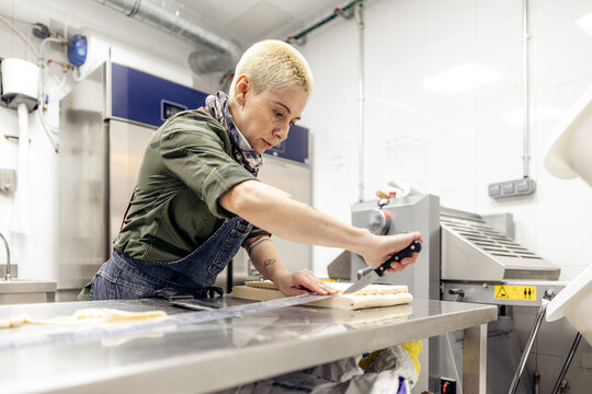 Pastry chef precisely cutting dough in professional kitchen