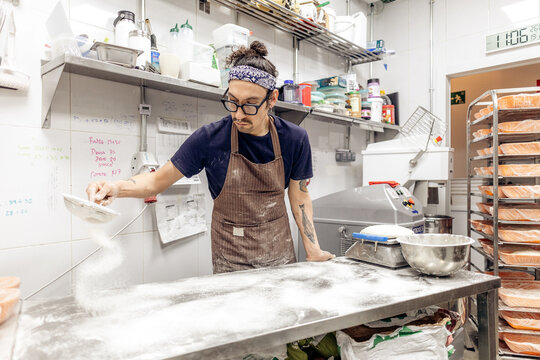 Male baker sifting flour in professional kitchen