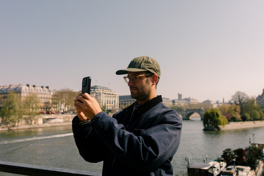 Tourist using a smartphone to take photos of the Seine River in Paris