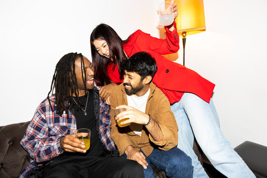 Friends hanging out at home party laughing and drinking 