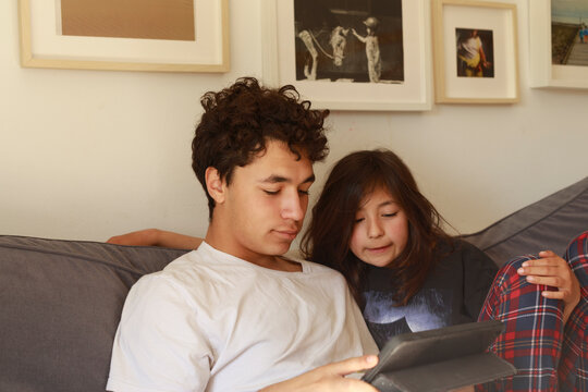 Brother and sister smiling at tablet