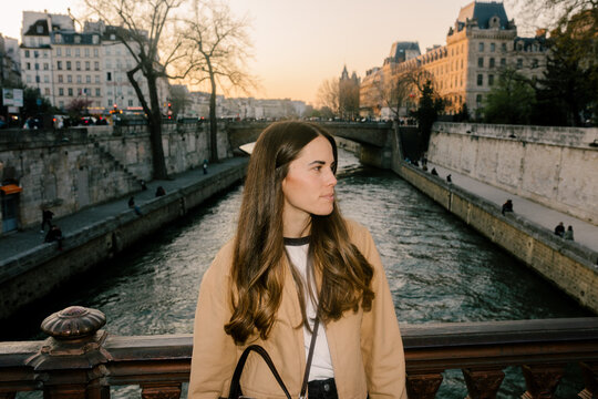 Portrait lit by flash of a female tourist posing by the Seine River