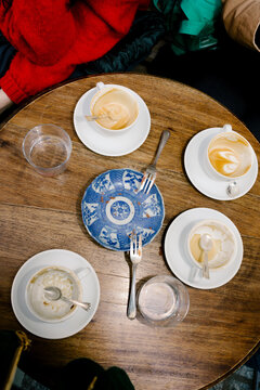 A wooden table with dirty plates and cups