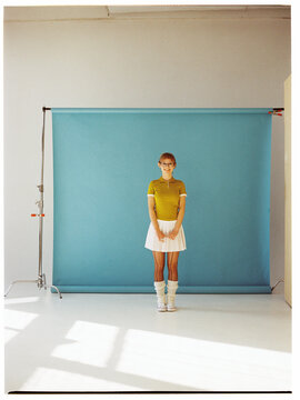 Young woman stands in front of blue backdrop in studio