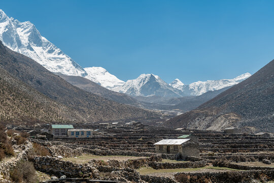 Remote Himalayan village beneath snow covered mountain peaks