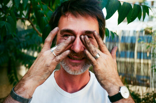 man rubbing his eyes with dirty hands