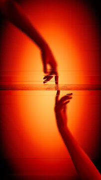 Hands touch behind frosted glass in warm light