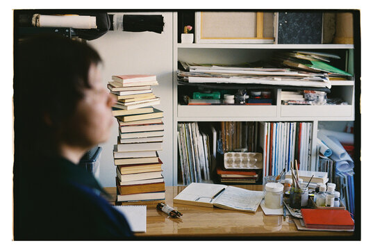 Artist stands in studio with art supplies