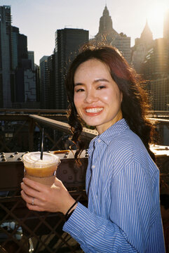 Beautiful woman stands on the Brooklyn Bridge at sunset