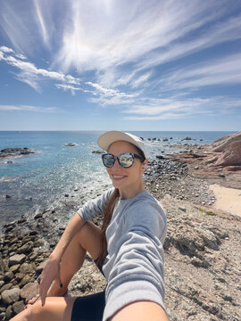ugc selfie of female sitting on a cliff and looking into camera