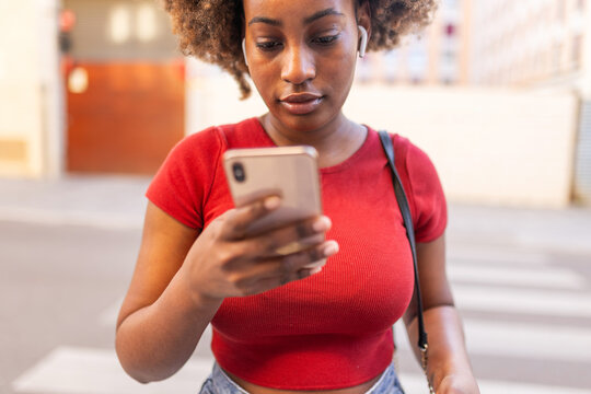 Close-up of a black woman using her mobile phone on the street.
