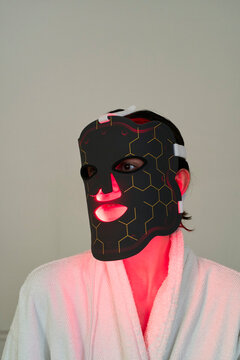 Person Wearing a Red Light Therapy Mask at Home for Skin Care