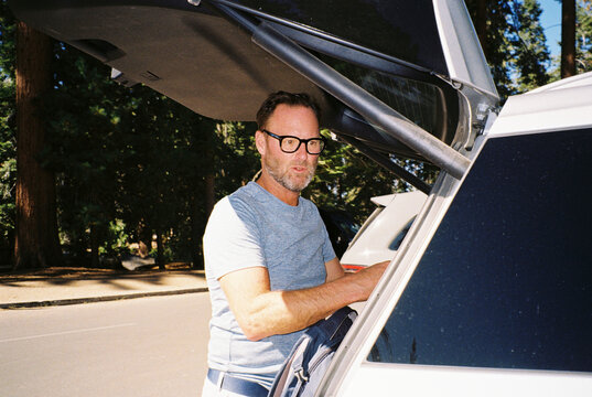 Man packs his luggage into the trunk of a car