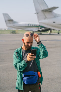 Man using smartphone on airport tarmac near airplanes