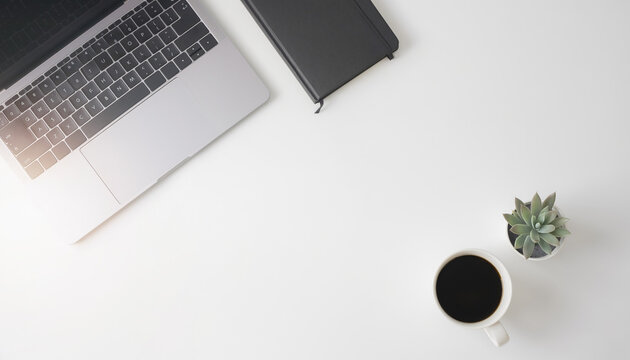 Minimal modern office desk flat lay with laptop notebook coffee and plant on white background, overhead view with copy space