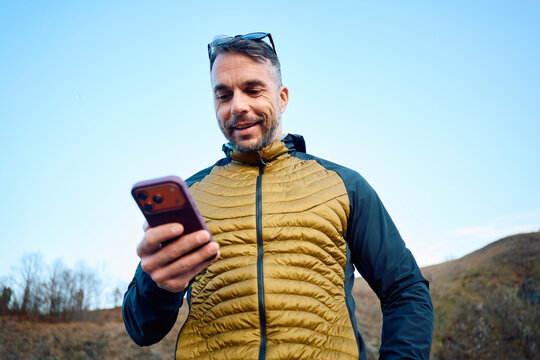 Casual man stands in nature, uses his phone