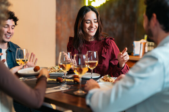 Young friends enjoying dinner and socializing at restaurant