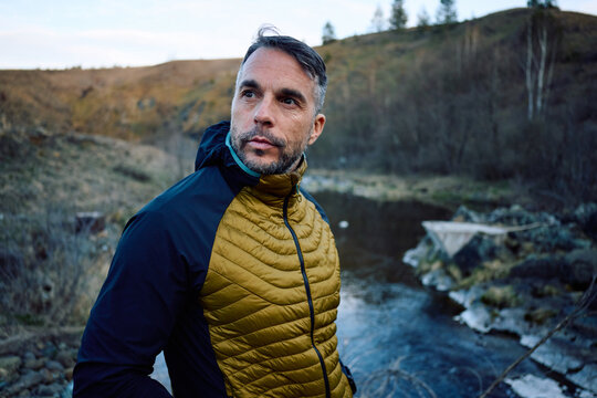 Handsome man stands by the mountain creek